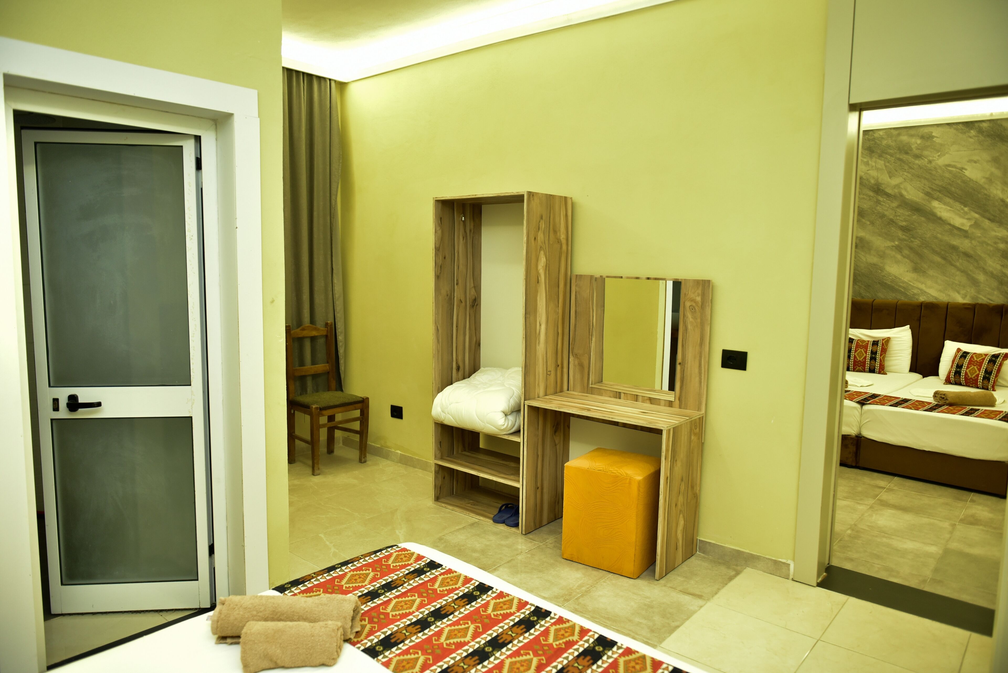 A hotel room with a bed, a wooden wardrobe, a small table, and a chair.