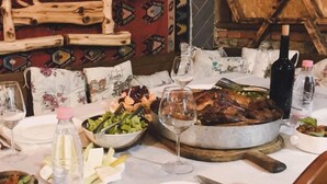 A dining table set with a roasted meat dish, salad, and various side dishes. - Te Bujtina Hotel&Restaurant (Golem)