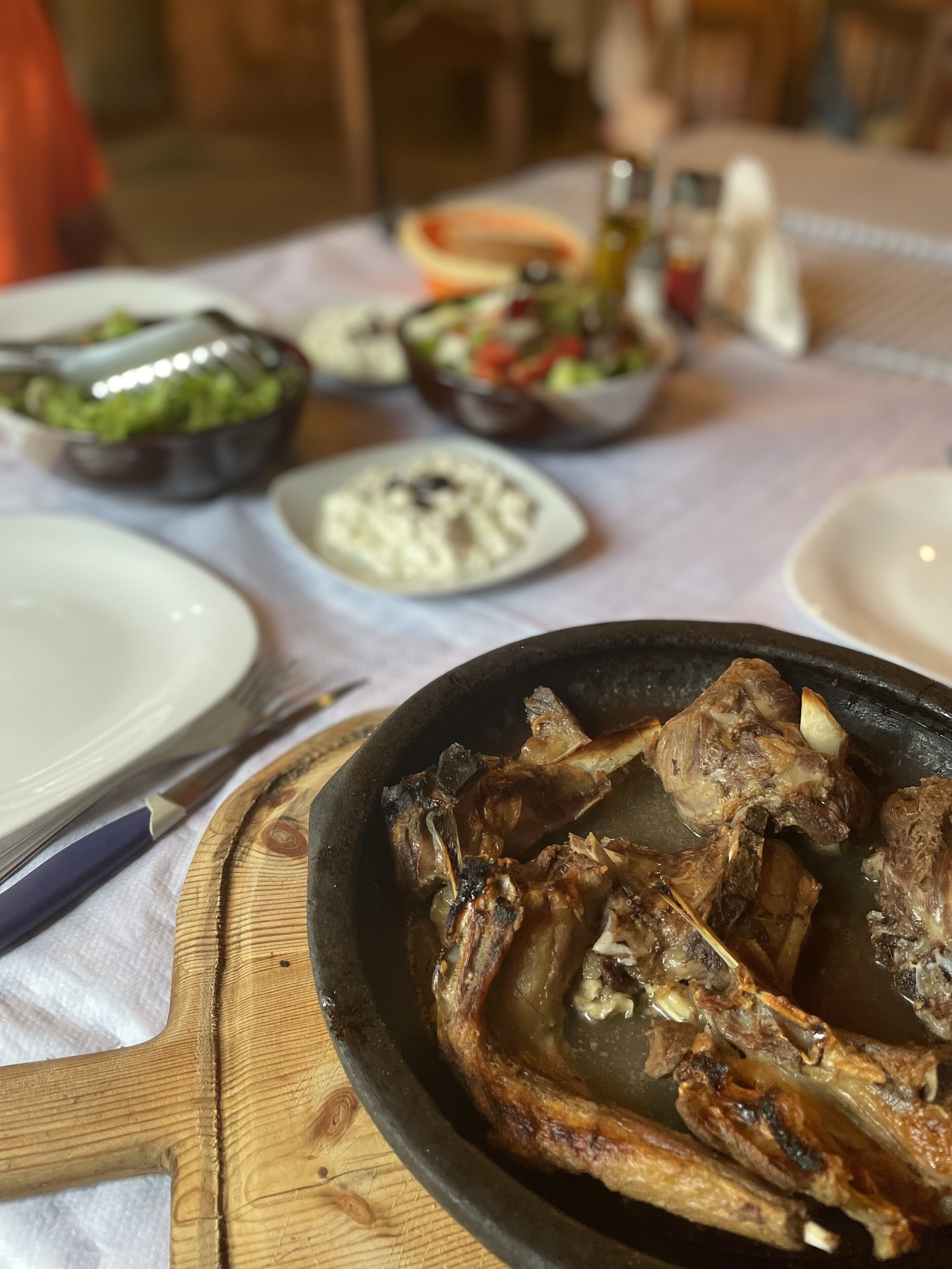 A dining table with a variety of dishes including roasted meat, salads, and a bowl of soup.