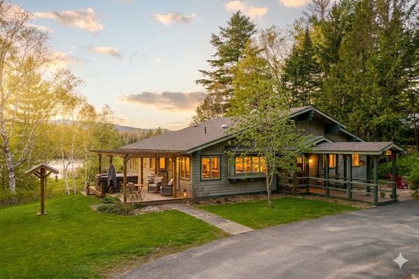 A cabin with a deck, a covered outdoor seating area, and a view of a lake.