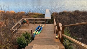 A wooden deck with a kayak and oars, a small table, and a lantern. - Waterfront w/ Kayaks, Paddleboards and a Hot Tub (Tupper Lake)