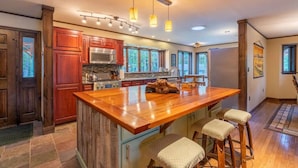 A spacious kitchen with a large island, wooden cabinets, stainless steel appliances, and pendant lighting. - Waterfront w/ Kayaks, Paddleboards and a Hot Tub (Tupper Lake)