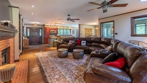 A spacious living room with a leather sectional sofa, a fireplace, and a large rug. - Waterfront w/ Kayaks, Paddleboards and a Hot Tub (Tupper Lake)