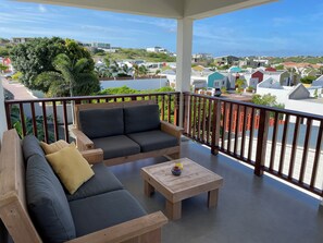Ein Balkon mit einer Holzsofa, einem kleinen Tisch und Blick auf eine Wohngegend.