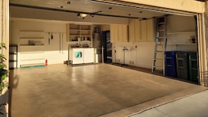 A garage with a washing machine, a refrigerator, and shelves with various items.