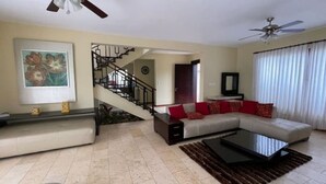 Ein Wohnzimmer mit einer Couch, einem Couchtisch, einer Treppe und einem Fernseher.