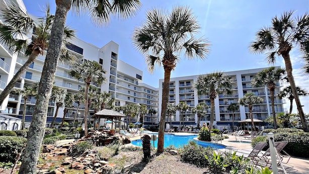 Ein Resort mit Schwimmbad, Palmen und einem felsigen Bereich.