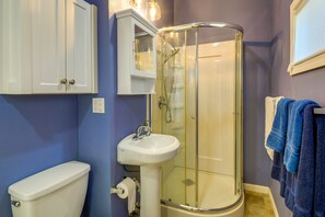 Une salle de bain comprenant des toilettes, un lavabo et une douche fermée par une paroi en verre.