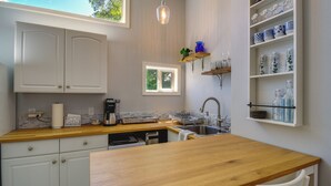 A kitchen with white cabinets, a wooden countertop, a sink, and a window. - Waterfront Hood Canal Cottage: Steps to the Beach! (Belfair)