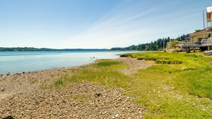 A lakeside property with a rocky shoreline, grassy areas, and a view of the lake. - Waterfront Hood Canal Cottage: Steps to the Beach! (Belfair)