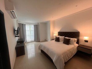 A hotel room with a large bed, two bedside tables with lamps, a flat-screen TV mounted on the wall, and a window with curtains. - Hotel Zuriel Boutique (Cartagena)
