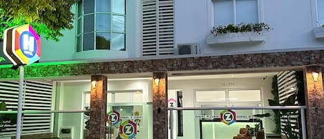 A hotel with a modern facade, large windows, and a visible entrance with a sign.