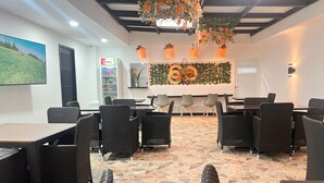 A restaurant with wicker furniture, stone flooring, and a wall decorated with a number '60' and floral arrangements. - Hotel Zuriel Boutique (Cartagena)