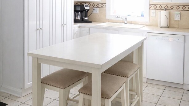 Une cuisine avec des meubles blancs, un plan de travail blanc et une fenêtre.
