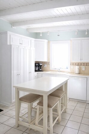 Una cocina con armarios blancos, encimera blanca y ventana.