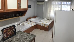 A compact hotel room with two single beds, a kitchenette, a refrigerator, and a window with curtains. - Joey Pansiyon (Marmara)