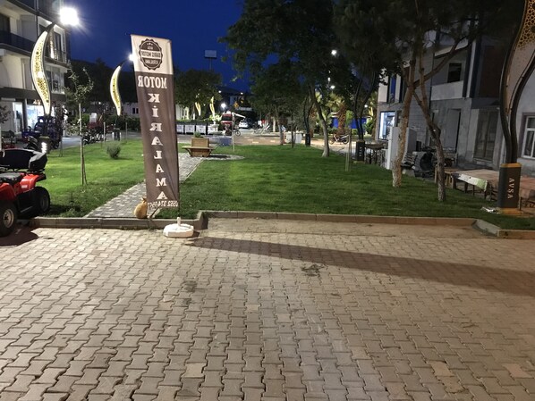 Un área pavimentada con un letrero que dice 'MOTOK AJAMA' y un césped.