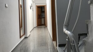 A hallway with a tiled floor, wooden doors, and a visible kitchen area in the background. - Joey Pansiyon (Marmara)