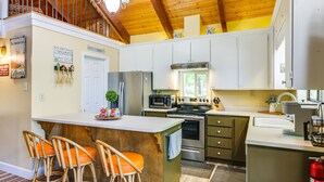 A kitchen with white cabinets, a stainless steel refrigerator, and a wooden island with bar stools. - Groveland Home - Walk to Pine Mountain Lake! (Groveland)