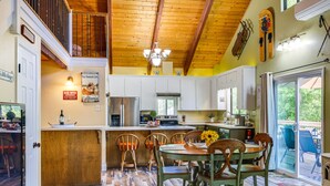 A kitchen with wooden flooring, a dining area with a table and chairs, and a view of the outdoors through a sliding glass door. - Groveland Home - Walk to Pine Mountain Lake! (Groveland)