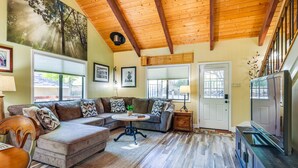 A cozy living room with a sectional sofa, a round coffee table, and a television on a wooden cabinet. - Groveland Home - Walk to Pine Mountain Lake! (Groveland)