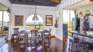 Un comedor rústico con una mesa y sillas de madera, un colgante de luz y obras de arte en las paredes.