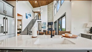 A spacious kitchen with a large island, stainless steel appliances, and a stone accent wall. - Pet-Friendly Game Retreat for Families and Groups (Broken Bow)