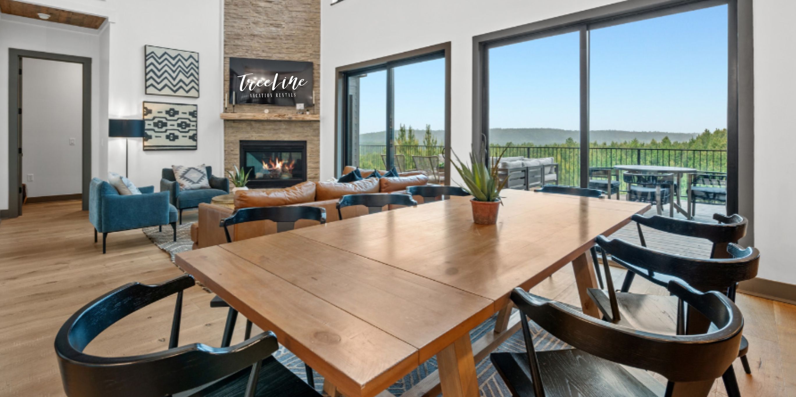 A spacious living area with a fireplace, a large wooden table, and a view of the outdoors.