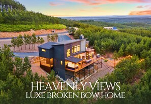 A multi-story luxury home with a prominent balcony, surrounded by a forested landscape. - Pet-Friendly Game Retreat for Families and Groups (Broken Bow)
