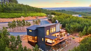 A modern two-story house with a deck, surrounded by dense forest and a view of the landscape. - Pet-Friendly Game Retreat for Families and Groups (Broken Bow)