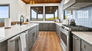 A modern kitchen with a wooden ceiling, large windows, and a view of the outdoors. - Pet-Friendly Game Retreat for Families and Groups (Broken Bow)