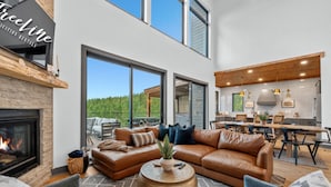 A modern living room with a fireplace, leather sofas, and a dining area with wooden furniture. - Pet-Friendly Game Retreat for Families and Groups (Broken Bow)