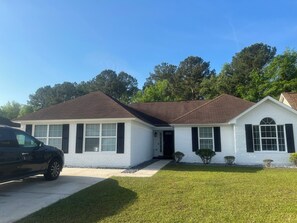 A two-story house with a brown roof, white exterior, and black shutters.