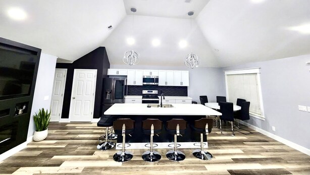 Una cocina moderna con una isla central, taburetes de bar e iluminación colgante.