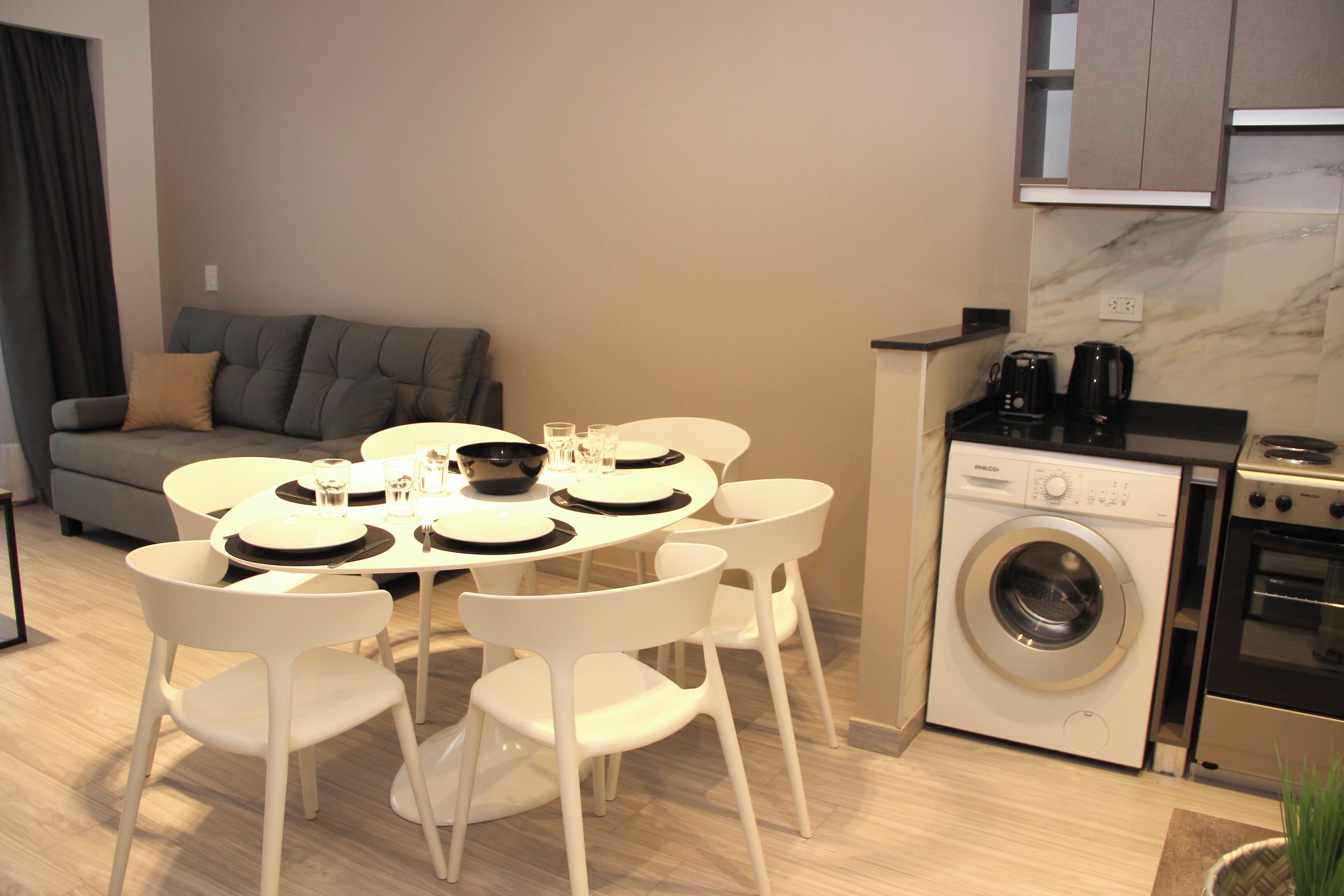 Un espacio habitable compacto con comedor, sofá, lavadora y cafetera.