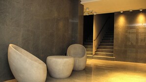A modern lobby with a staircase, three sculptural seating areas, and a polished floor. - In House BA - Le Coq (Buenos Aires)
