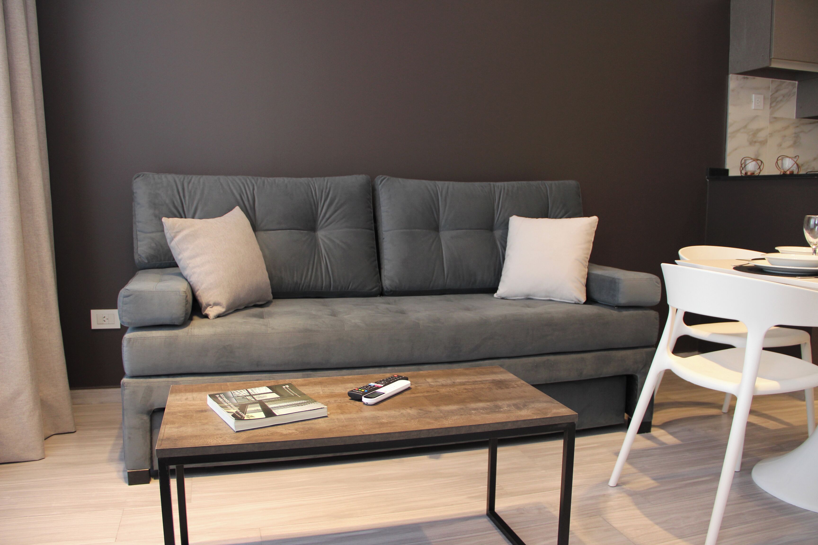 A modern living room with a grey sofa, a wooden coffee table, and a white chair.