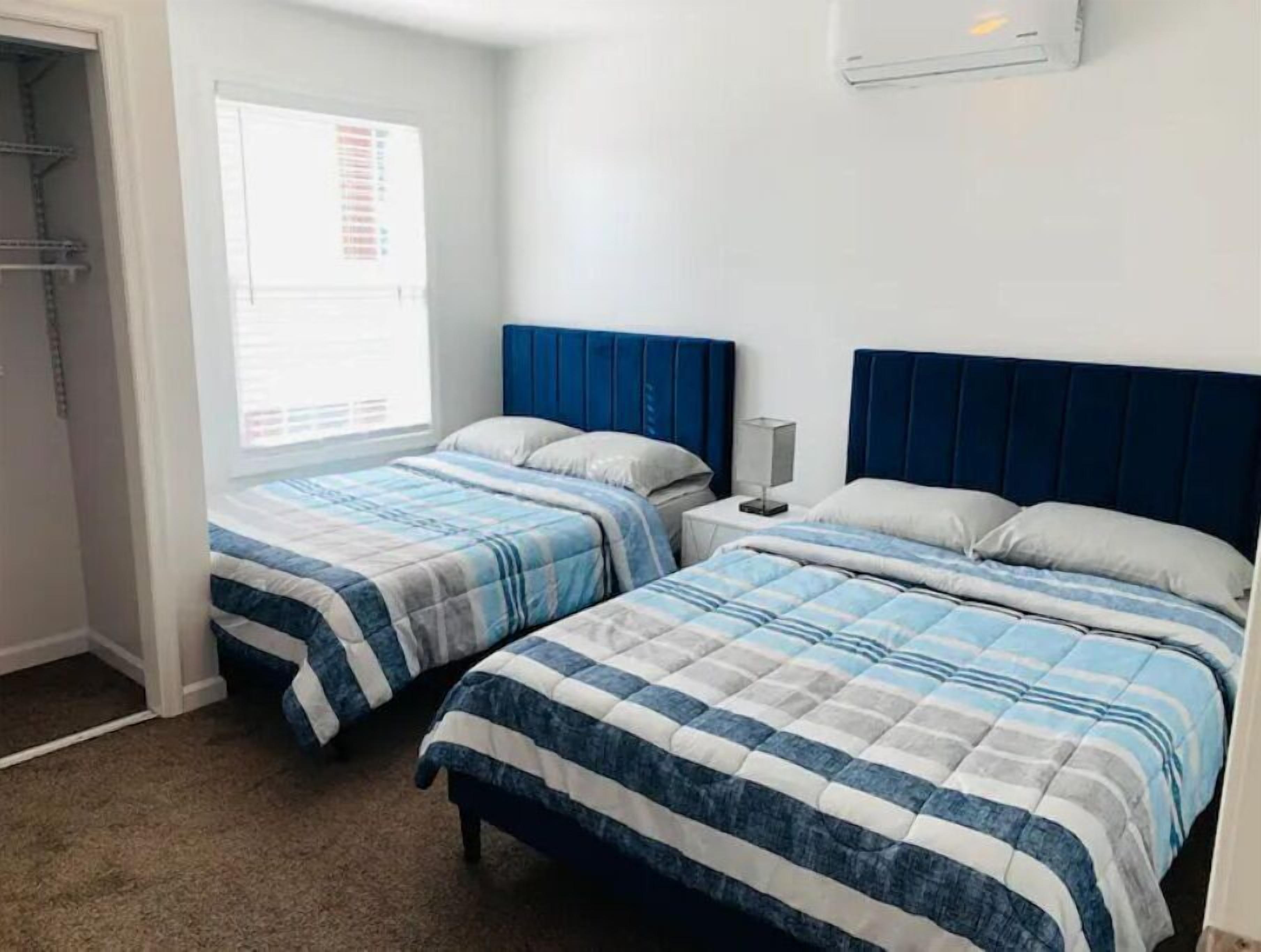 A bedroom with two beds, each with a blue headboard and striped bedding.