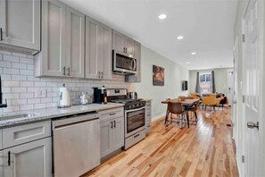 Kitchen features stainless steel appliances, light gray cabinetry, and a white tiled backsplash.