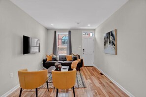 Relax in this stylish living room with a sofa, armchairs, and a flat-screen TV.