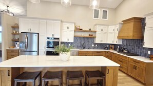 A modern kitchen with a large island, stainless steel appliances, wooden cabinets, and pendant lighting. - Beautiful, remodeled home on Lake Andrew with optional Pontoon Rental! (New London)