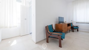 Un salón amplio con un aparador de madera, un televisor y dos sillones.