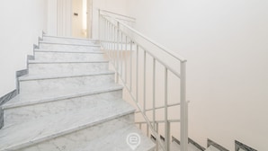Una escalera con escalones de mármol blanco y barandilla metálica blanca.