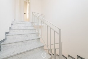 Un escalier avec des marches en marbre blanc et une rampe en métal blanc.
