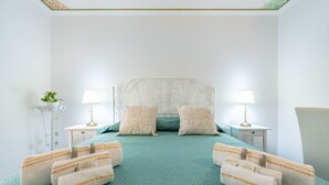 Ein aufgeräumtes Hotelzimmer mit einem Bett, das zwischen zwei Nachttischen platziert ist, jeweils mit einer Lampe und einem kleinen Tisch.