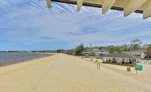 A beach with a row of houses and a building with a red cross sign, indicating a medical facility.