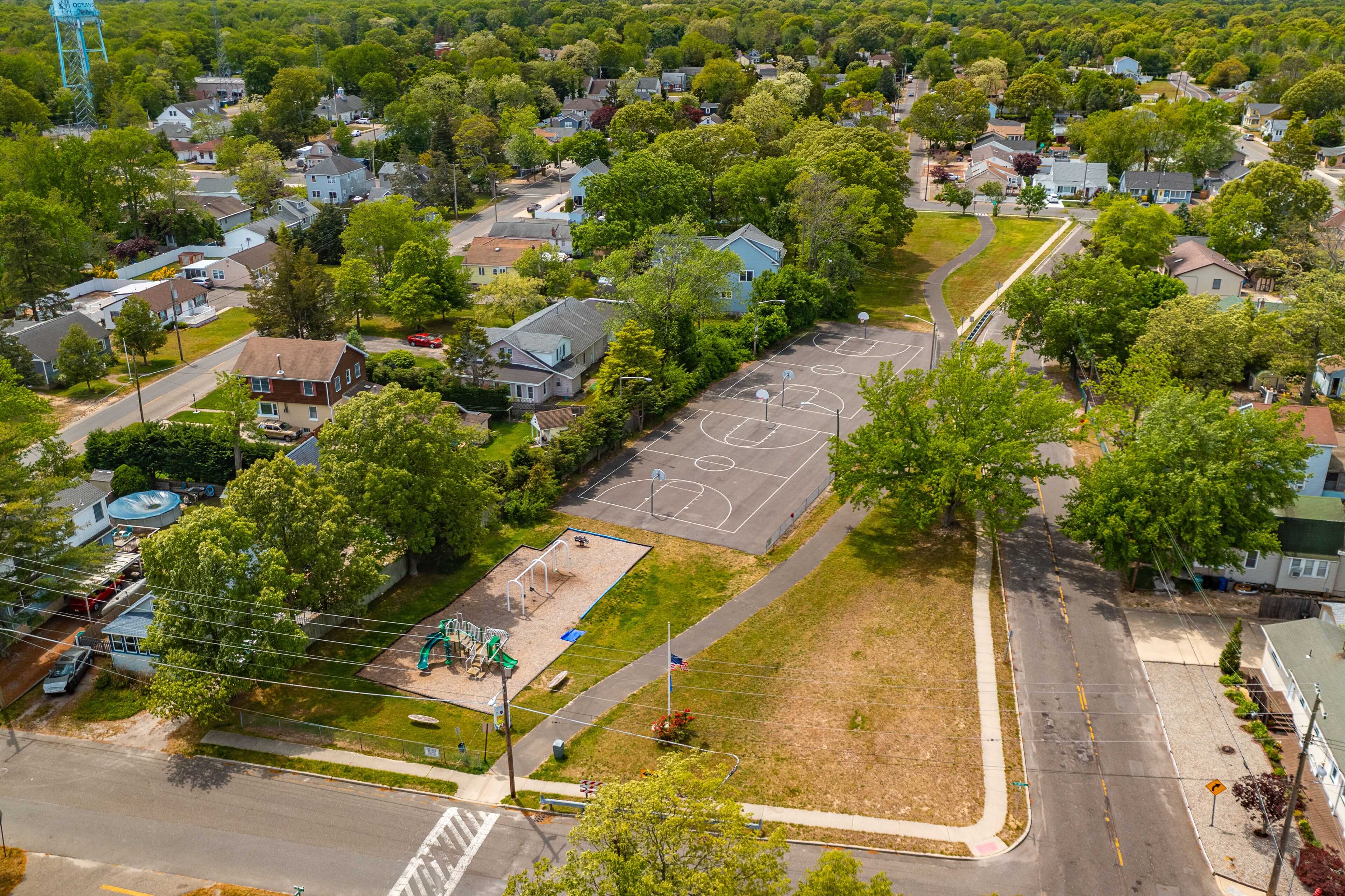 Vista aérea de un área residencial con casas, una cancha de baloncesto y un parque infantil.