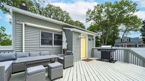 Une terrasse couverte avec des meubles d’extérieur, un barbecue et le numéro de la maison, 211.