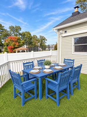A blue outdoor dining set with a white fence and a house in the background.