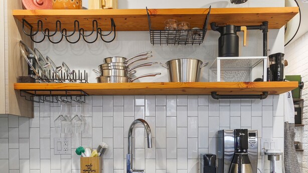 A kitchen with wooden cabinets, a stainless steel dishwasher, a coffee maker, and a hanging pot rack.